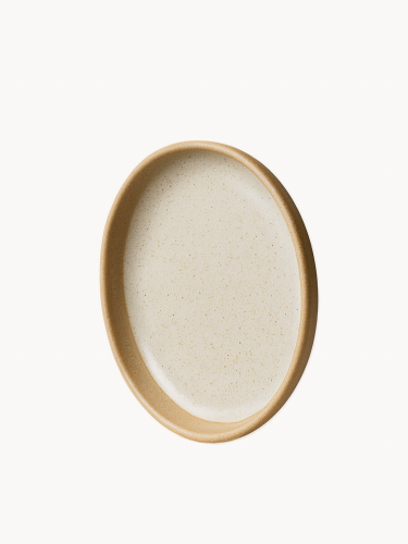 Okrągły ceramiczny talerz z nakrapianym, jasnoszarym szkliwionym wnętrzem i grubym, nieszkliwionym rantem z naturalnej terakoty, przedstawiony w pionowej pozycji na jasnym tle.