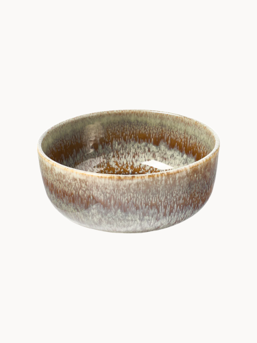 Okrągła ceramiczna miska pokryta błyszczącym szkliwem, w którym ziemisty brąz spływa w teksturowane, jasnobeżowe i szare wykończenie,  na jednolitym białym tle.